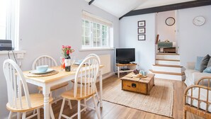 A cozy living space with a dining area, a television, and a staircase. - The Grapes, Holiday Cottage Penally, Sleeps 2, 1 bedrooms,  bathrooms (TENBY)