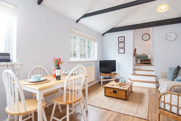 A cozy living space with a dining area, a television, and a staircase.