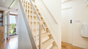 Una escalera con barandilla de madera y escalones color beige que conducen a una puerta.