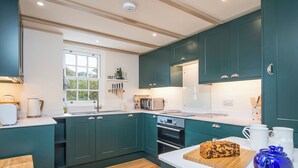 Una cocina moderna con armarios color turquesa, encimera de madera y varios electrodomésticos, incluyendo un microondas, tostadora y horno.