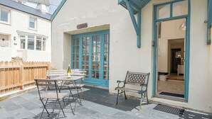 A patio area with a table and chairs, a bench, and a door leading to an interior space. - The Old Butchers Shop, Holiday Cottage Little Haven, Sleeps 2, 1 bedrooms,  bathrooms (Haverfordwest)