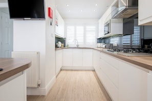 Eine moderne Küche mit weißen Schränken, einer Holz Arbeitsplatte und einem eingebauten Kochfeld.
