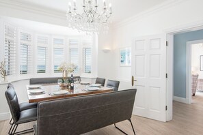 A dining room with a large table, chairs, and a chandelier.