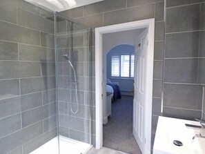 A modern bathroom with a glass-enclosed shower, a white sink, and a visible bedroom with a bed and window. - The Rath, Holiday Cottage Saundersfoot, Sleeps 6, 3 bedrooms,  bathrooms (SAUNDERSFOOT)