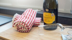 A bottle of Prosecco wine, a rolled-up red and white striped cloth, and a clear glass on a wooden surface. - The Rath Cottage, Holiday Cottage Saundersfoot, Sleeps 2, 1 bedrooms,  bathrooms (SAUNDERSFOOT)