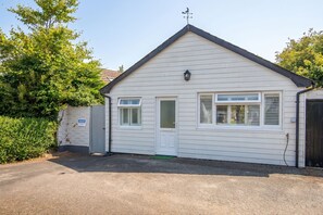 A single-story building with a white exterior, a front door, two windows with shutters, and a small porch area. - The Rath Cottage, Holiday Cottage Saundersfoot, Sleeps 2, 1 bedrooms,  bathrooms (SAUNDERSFOOT)