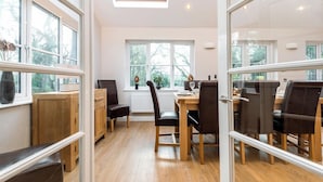 Un espace repas avec une table et des chaises en bois, une lucarne et de grandes fenêtres.