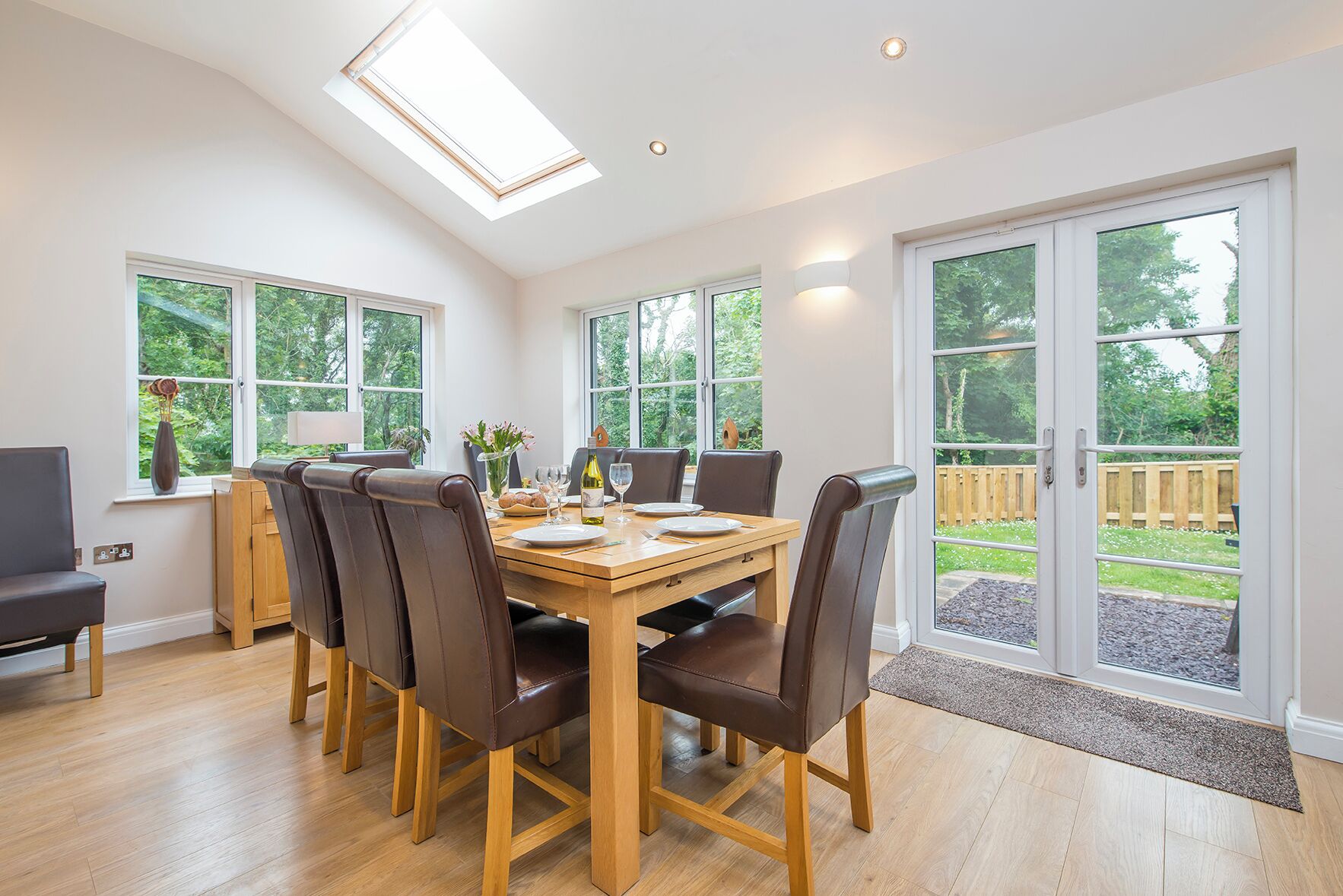 A dining area with a wooden table, six chairs, and a large window.