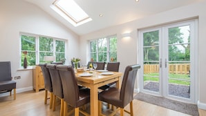 Un coin repas avec une table en bois, six chaises et une grande fenêtre.