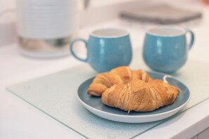 A plate with two croissants on a blue plate, placed on a light blue table.