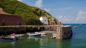A coastal scene with a small white building, a stone wall, and boats docked at a pier. - The Smithy, Holiday Cottage Abercastle, Sleeps 2, 1 bedrooms,  bathrooms (Haverfordwest)