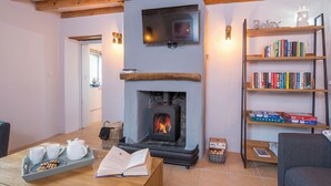 A cozy living room with a fireplace, a bookshelf, and a table with tea set and snacks. - The Stables and Bullpen, Holiday Cottage Castlemartin, Sleeps 6, 3 bedrooms,  bathrooms (Pembroke)