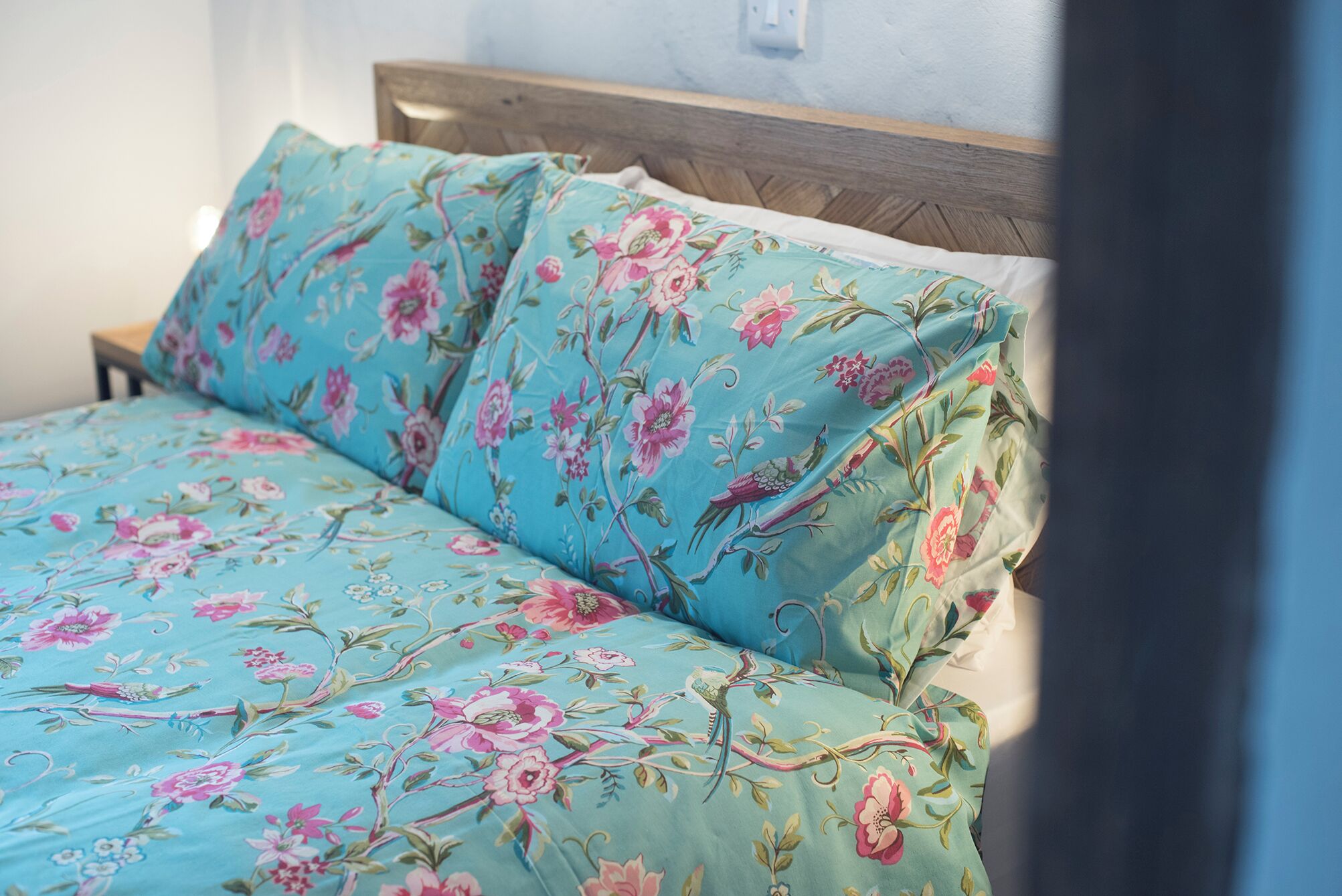 A bed with floral bedding and a wooden headboard.