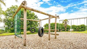 A playground with a tire swing, a rope climbing structure, and a swing set. - The Woolpack, Holiday Cottage Ivy Tower Village, St Florence, Sleeps 6, 3 bedrooms,  bathrooms (Tenby)
