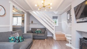A modern living room with a grey sofa, a smaller grey sofa, and a staircase leading to an upper level. - The Woolpack, Holiday Cottage Ivy Tower Village, St Florence, Sleeps 6, 3 bedrooms,  bathrooms (Tenby)
