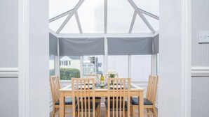 A conservatory with a wooden dining table and chairs, large windows, and a view of the outside. - The Woolpack, Holiday Cottage Ivy Tower Village, St Florence, Sleeps 6, 3 bedrooms,  bathrooms (Tenby)