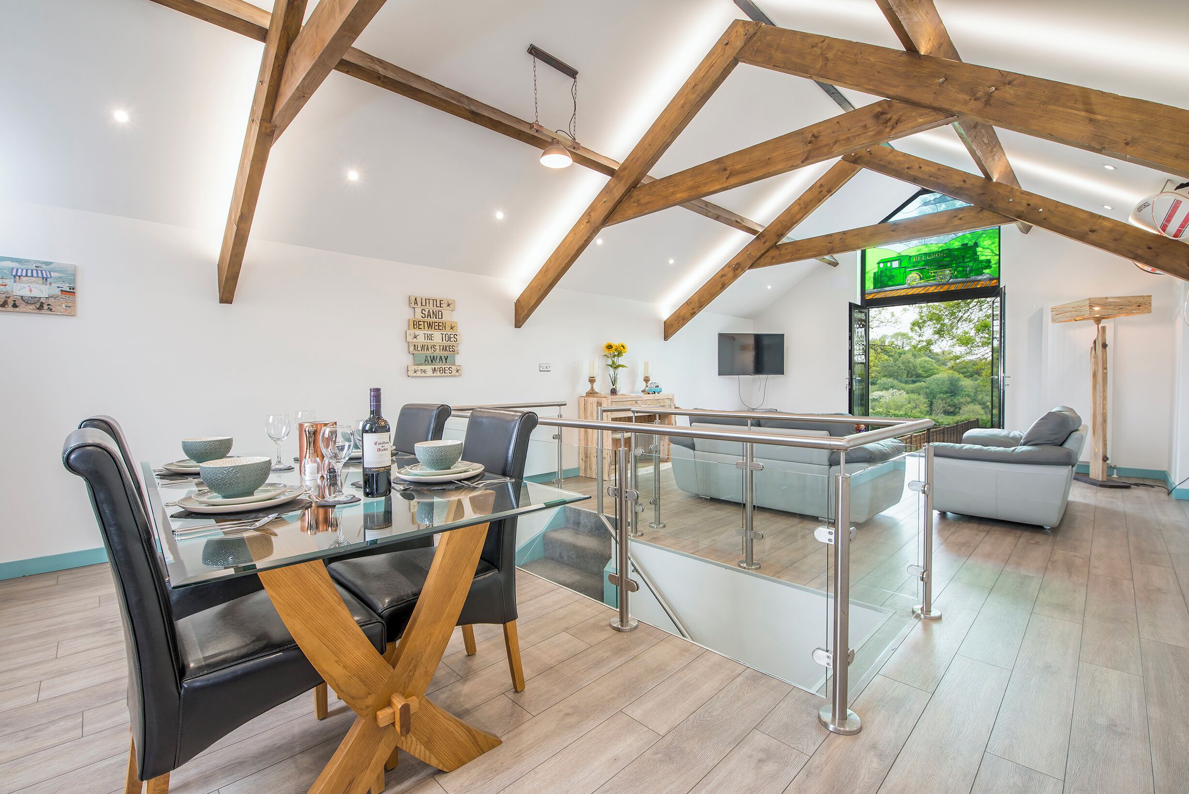 A modern dining area with a glass table, wooden beams, and a view of the outdoors.
