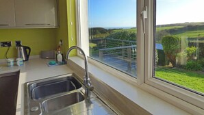 A kitchen with a large window, a sink, and a kettle.