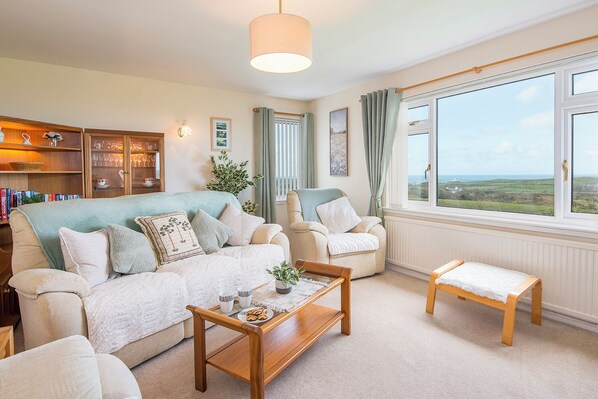 A cozy living room with a sofa, armchairs, a coffee table, and a view of the countryside through large windows. - Trefisheg Bungalow, Holiday home Strumble Head, Sleeps 6, 3 bedrooms,  bathrooms (Strumble Head)