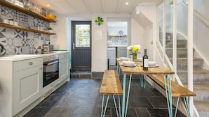 Une cuisine moderne dotée d’un îlot central, d’un four encastré et d’un coin repas avec une table et des bancs en bois.