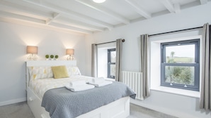 Une chambre à coucher moderne avec un lit, des lampes de chevet, une vue par la fenêtre et un radiateur.