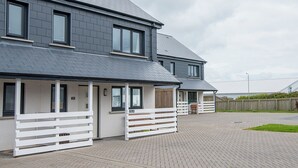 Ein modernes, zweistöckiges Haus mit gepflasterter Auffahrt und weißem Zaun.