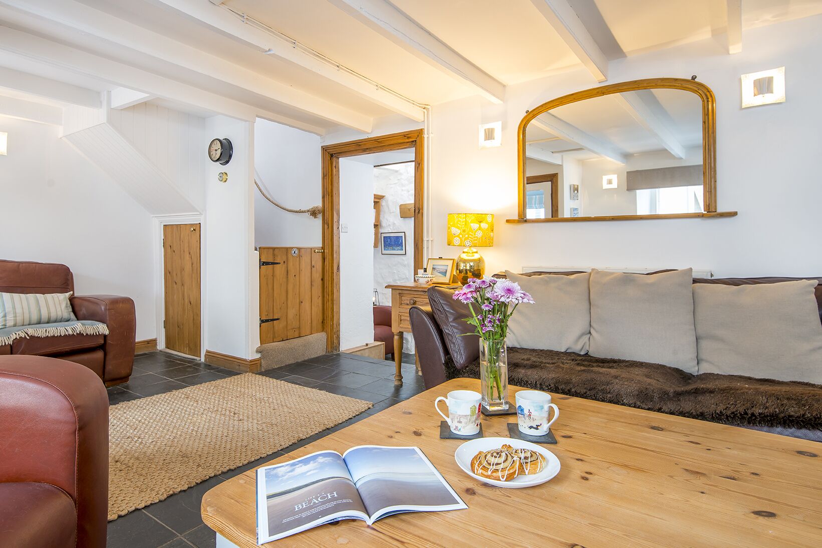 Een gezellige woonkamer met een houten salontafel, een bank en een zithoek met een boek en een bord eten.