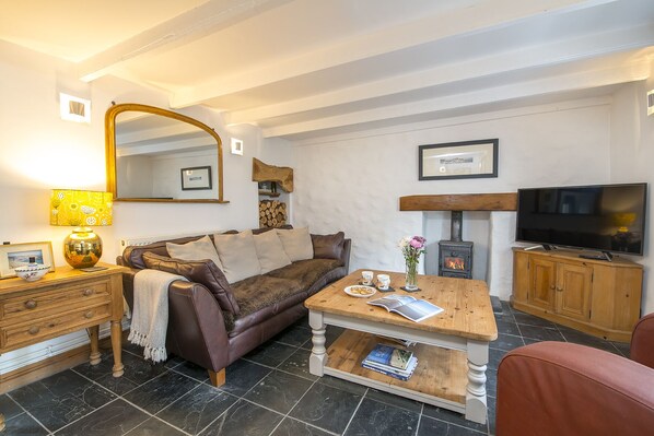 A cozy living room with a sofa, coffee table, TV, fireplace, and a mirror. - Ty Draw, Holiday Cottage Trefin, Sleeps 3, 2 bedrooms, bathrooms (Haverfordwest)