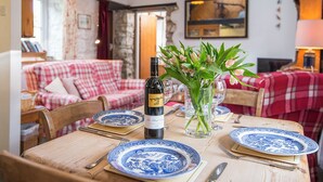 Une table à manger dressée avec de l’assiette bleue et blanche, une bouteille de vin et un vase rempli de fleurs.