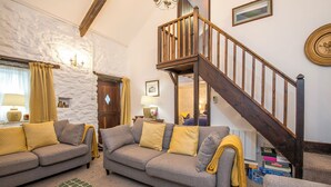 A cozy living room with a grey sofa set, a wooden staircase, and a stone wall. - Vagwr Eilw Cottage, Holiday Cottage Llanhowell, near Abereiddy, Sleeps 6, 3 bedrooms,  bathrooms (Haverfordwest)