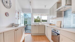 A modern kitchen with light-colored cabinets, a large window, and a view of the outdoors. - Valley View, Holiday Cottage Little Haven, Sleeps 6, 3 bedrooms,  bathrooms (Haverfordwest)