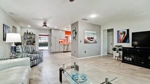 A spacious living room with a sofa, a glass coffee table, and a television.