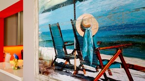 A beach scene with a chair and table, a hat, and a fish figurine on a shelf.