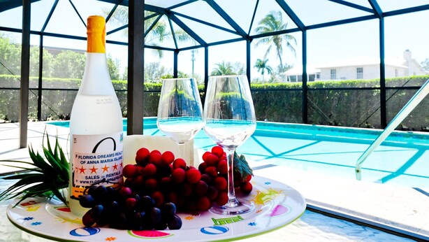 A table with a bottle, two glasses, and a plate of grapes.