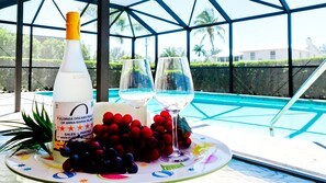 A table with a bottle, two glasses, and a plate of grapes. - Boater’s Paradise with Pool Near Anna Maria Island (Bradenton)