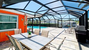 A covered patio with a pool, outdoor seating, and a grill area.