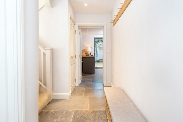 A narrow hallway with a bench, a door leading to another room, and a small table with a lamp in the background. - Welford, Holiday Home Newport, Sleeps 8, 4 bedrooms,  bathrooms (Newport)