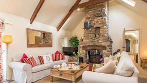 A cozy living room with a stone fireplace, a sofa, a coffee table with tea sets, and a TV.