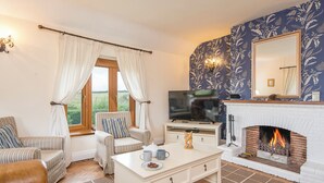 Ein Wohnzimmer mit Kamin, Fernseher und einem gestreiften Sessel.