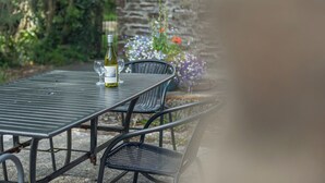 Een metalen tafel met een fles witte wijn en een glas, omringd door stoelen.