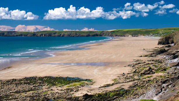 A coastal beach with a rocky shoreline, a sandy beach, and a clear blue sky.