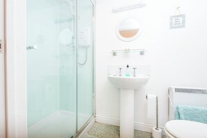 A bathroom with a glass shower enclosure, a white sink with a mirror above it, and a towel rack with a towel. - Y Bwthyn, Holiday Property Cwm Yr Eglwys, Sleeps 2, 1 bedrooms,  bathrooms (Cwm yr Eglwys)