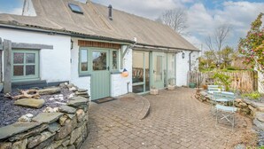 Un bâtiment blanc avec un mur en pierre et une terrasse dallée.