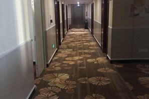 A hotel hallway with a patterned carpet, doors on both sides, and a fire extinguisher on the wall. - Jing'an Hostel (Jing'an)