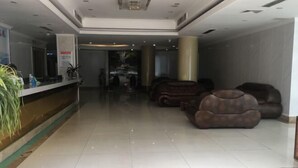 A hotel lobby with a reception desk, seating area, and a red carpet.