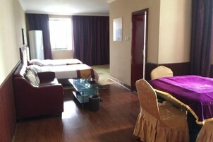 A hotel room with two beds, a sofa, a small table, and a chair.