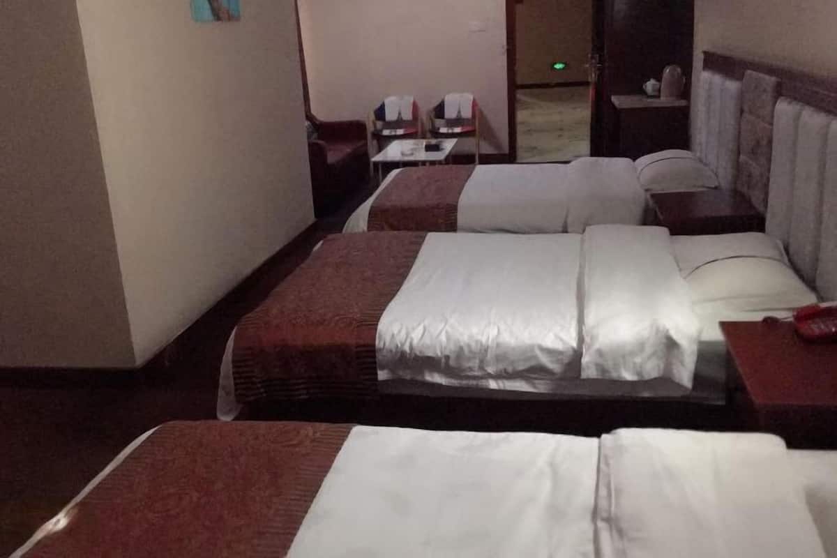 Una habitación de hotel con dos camas, una mesita pequeña y una silla.