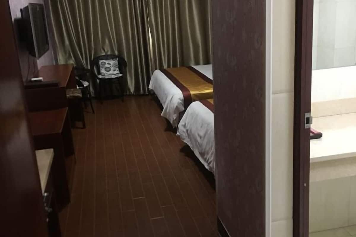 Habitación de hotel con dos camas, un escritorio, una silla y un televisor.