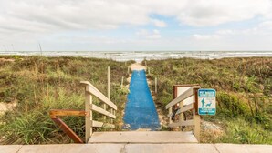 A pathway leading to a beach with a sign warning about pet waste.