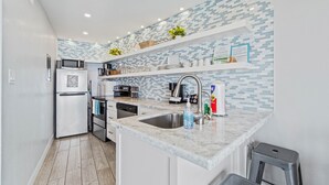A modern kitchen with white appliances, a stainless steel sink, and a tiled backsplash.